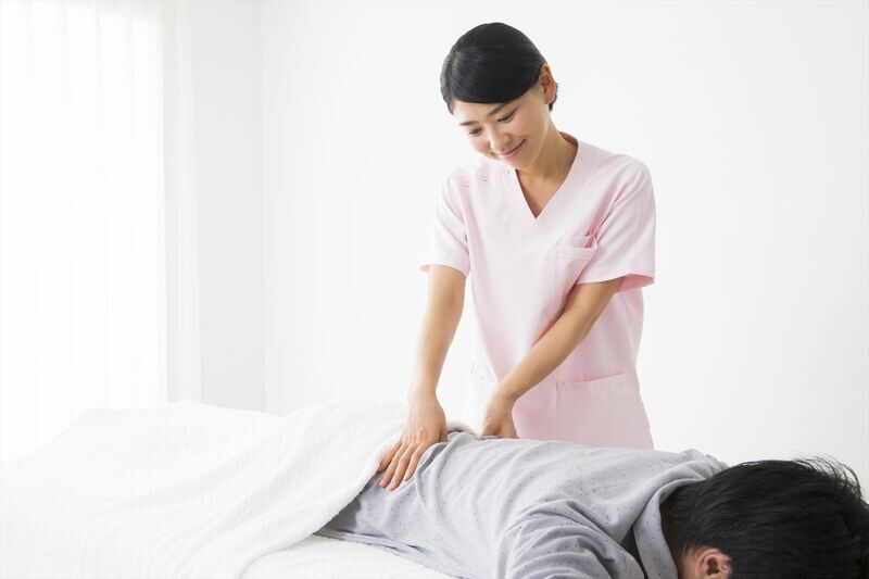 男性の腰を施術する女性スタッフ